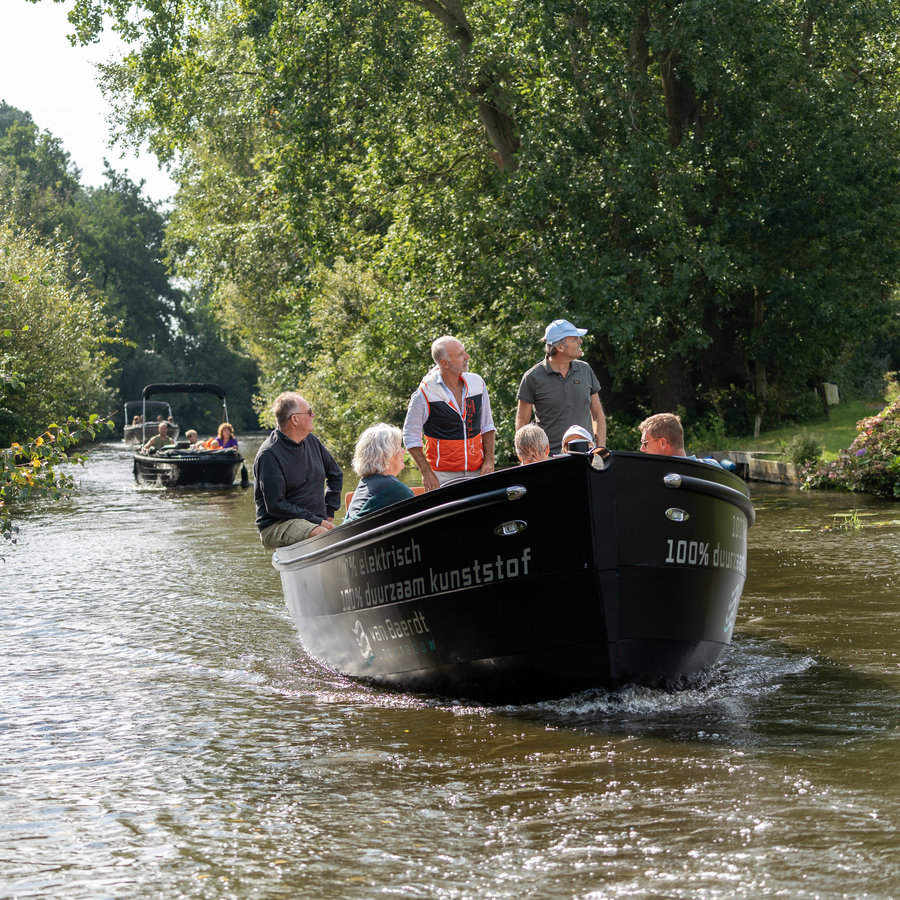 Gruppe von Menschen segelt mit einer Schaluppe durch Friesland