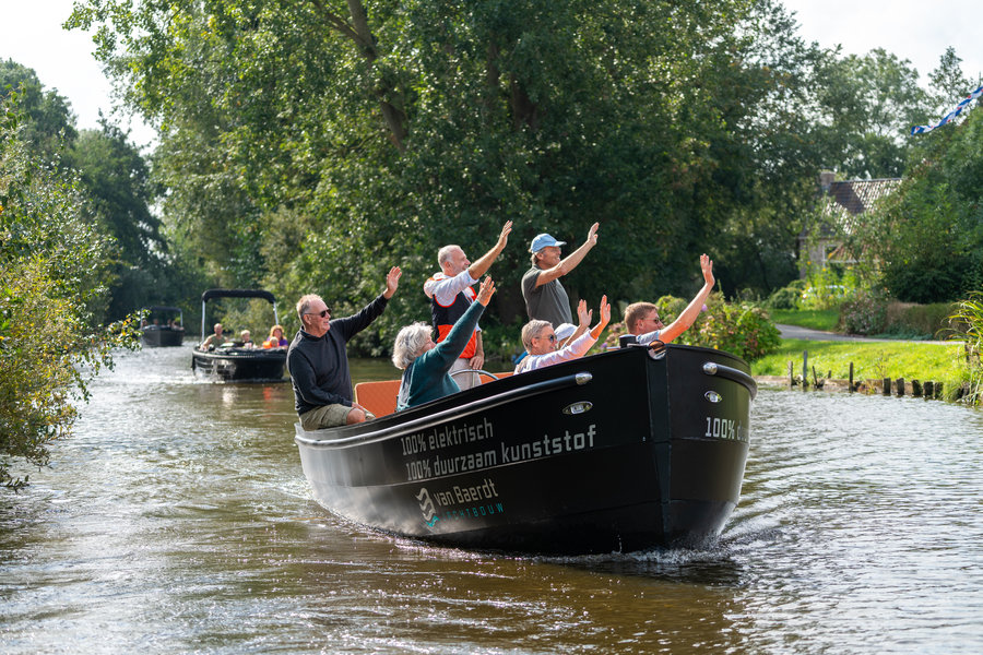 Eine Gruppe winkender Menschen auf einem Elektroboot